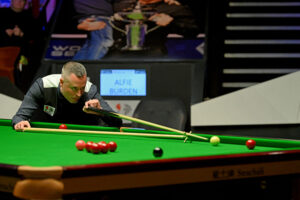 Alfie Burden playing a shot with the rest at the 2023 World Seniors Snooker Championship.